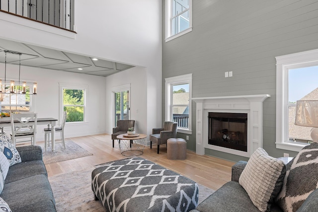 living area featuring a high ceiling, a fireplace, wood finished floors, and a notable chandelier