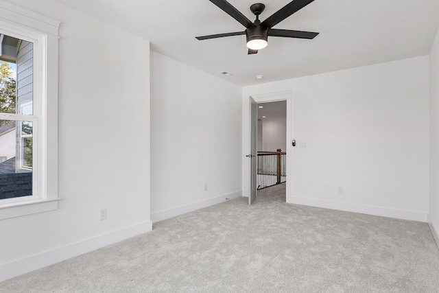 spare room with a ceiling fan, visible vents, baseboards, and carpet flooring