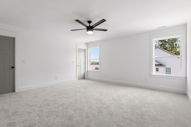 carpeted empty room with visible vents, a ceiling fan, and baseboards