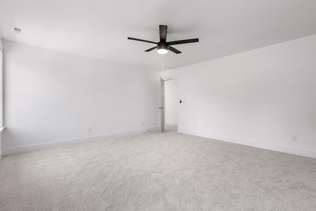 carpeted empty room with visible vents, ceiling fan, and baseboards