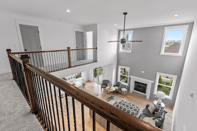 interior space with ornamental molding, a glass covered fireplace, a high ceiling, and recessed lighting