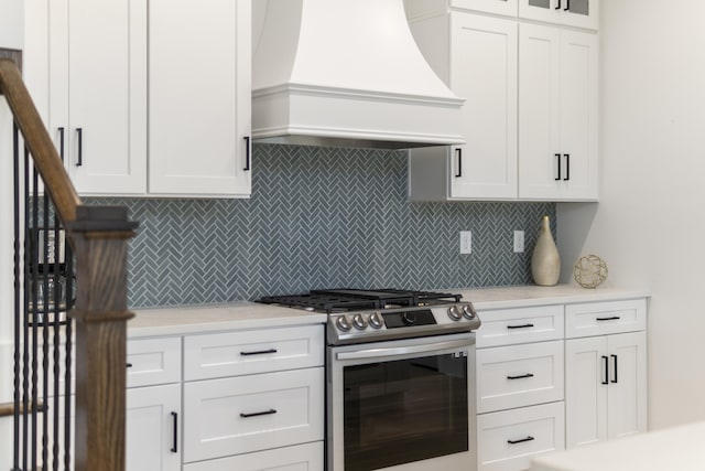 kitchen featuring white cabinetry, light countertops, custom exhaust hood, tasteful backsplash, and gas range