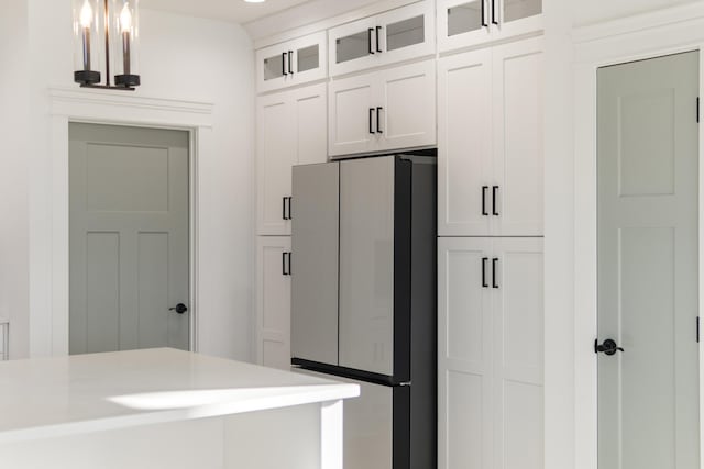 kitchen featuring glass insert cabinets, freestanding refrigerator, light countertops, and white cabinetry