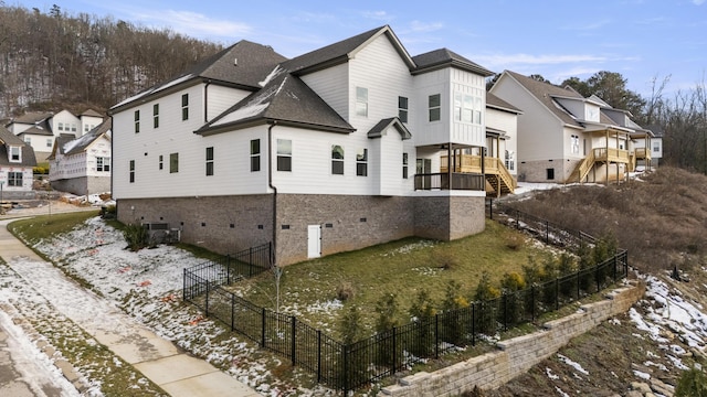 view of side of property with a residential view, stairway, roof with shingles, fence, and brick siding