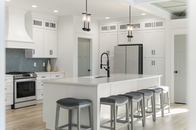 9891 Trestle Cir Unit 48, Ooltewah, TN 37363 - kitchen with stainless steel appliances, custom exhaust hood, light wood-style floors, backsplash, and light countertops