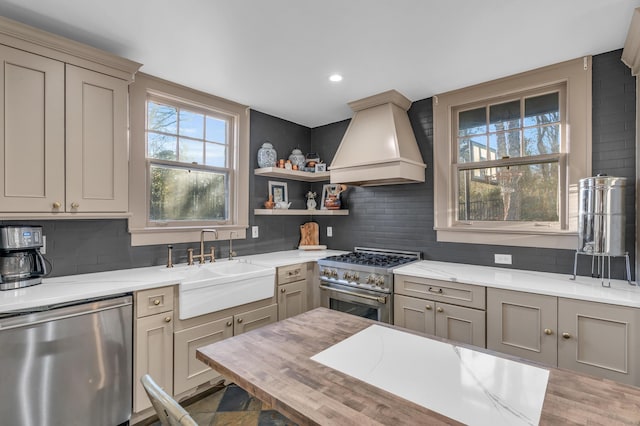 kitchen with custom range hood, a sink, stainless steel appliances, gray cabinetry, and backsplash