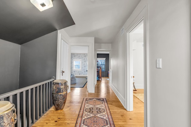 hall featuring visible vents, light wood-style flooring, and baseboards