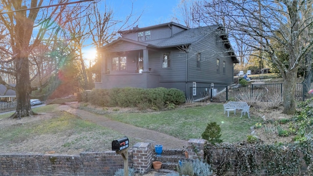 view of home's exterior with roof with shingles, fence, and a yard