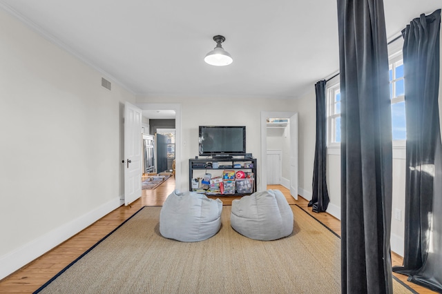 interior space featuring crown molding, wood finished floors, visible vents, and baseboards