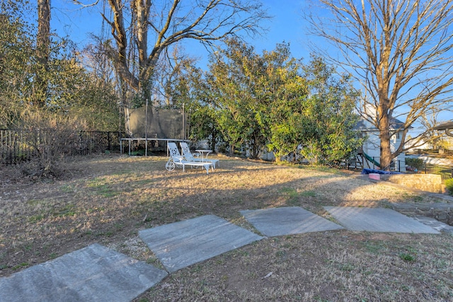 view of yard featuring a trampoline and fence