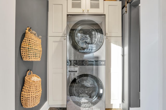 laundry room with stacked washer / dryer and cabinet space