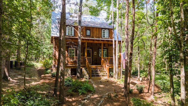 back of house featuring covered porch and stairway