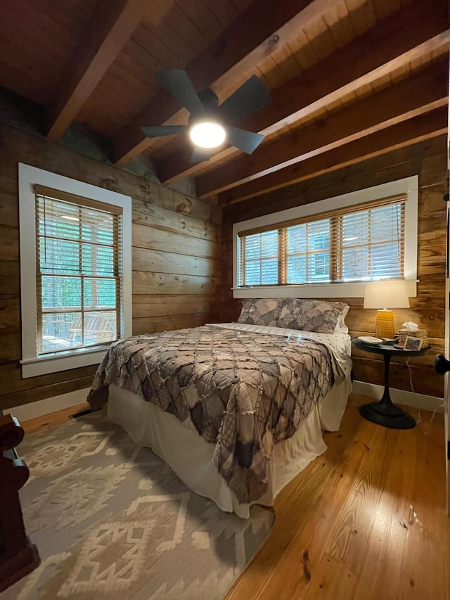 bedroom with wooden ceiling, beamed ceiling, wooden walls, and wood finished floors