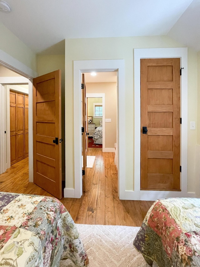 bedroom featuring baseboards, vaulted ceiling, and light wood finished floors