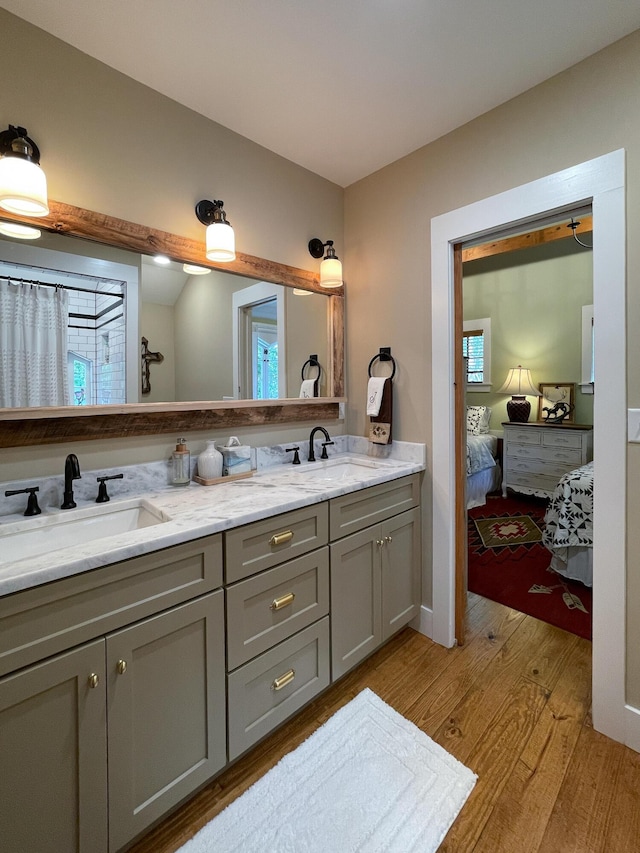 full bathroom with double vanity, wood finished floors, a sink, and ensuite bathroom