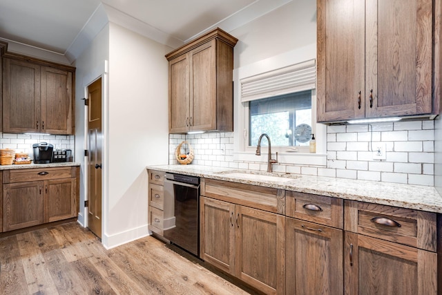 kitchen featuring light wood finished floors, decorative backsplash, a sink, light stone countertops, and dishwashing machine