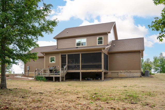 rear view of property featuring a deck, cooling unit, a shingled roof, a sunroom, and a lawn