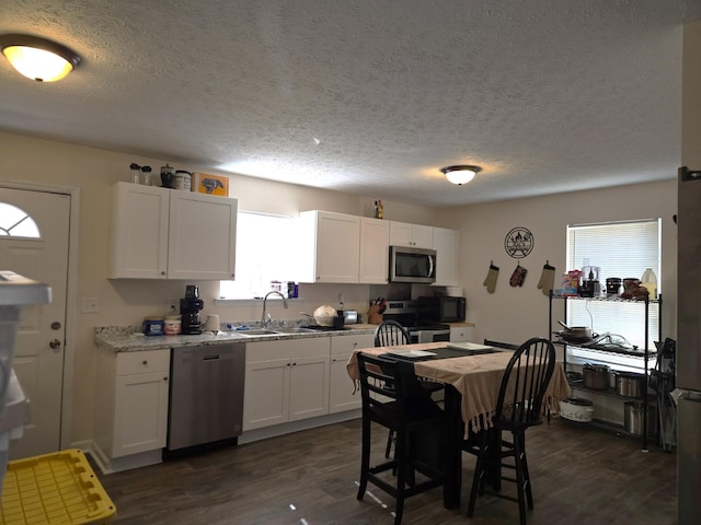 kitchen with white cabinets, appliances with stainless steel finishes, dark wood-style flooring, and a sink