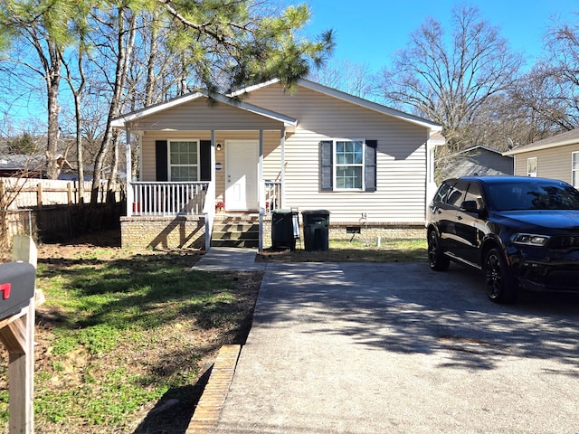 bungalow-style house with a porch, crawl space, fence, and driveway