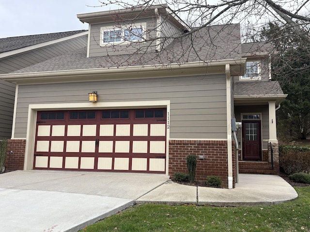 view of front of home featuring a garage, concrete driveway, brick siding, and roof with shingles