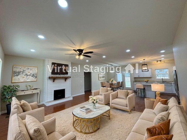 living room with dark wood-style flooring, recessed lighting, a ceiling fan, a large fireplace, and baseboards