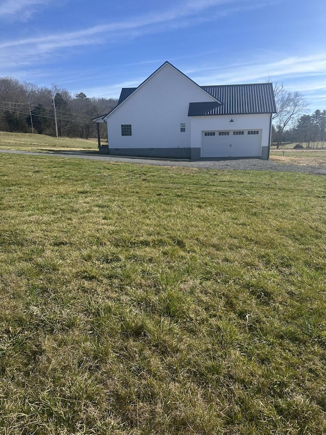 view of home's exterior with a garage, metal roof, and a lawn