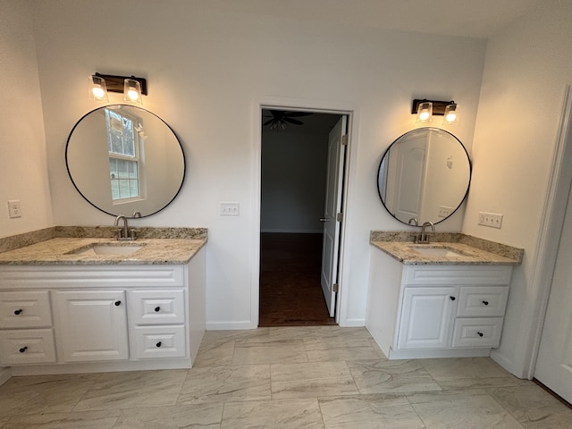 bathroom with marble finish floor, two vanities, and a sink