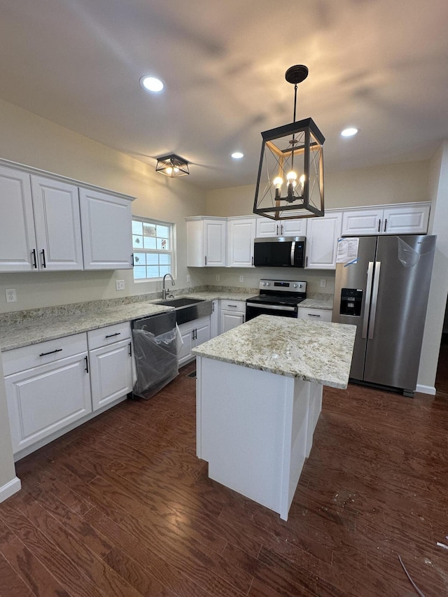 kitchen with stainless steel appliances, dark wood-type flooring, a sink, white cabinetry, and a center island