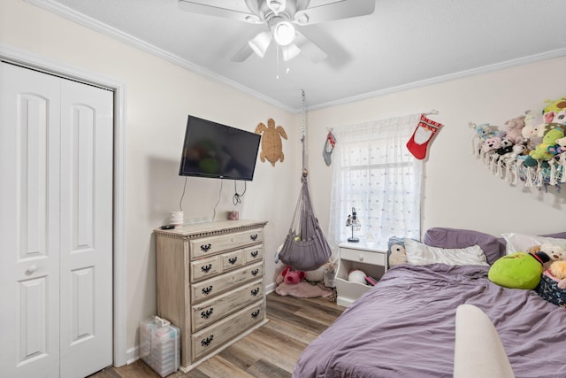 bedroom featuring ceiling fan, a closet, light wood-type flooring, and crown molding