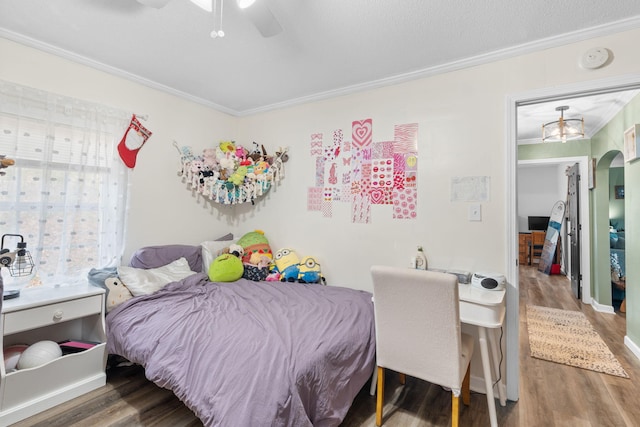 bedroom with ceiling fan, arched walkways, crown molding, and wood finished floors