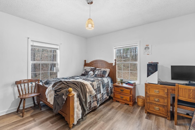 bedroom with a textured ceiling, multiple windows, and wood finished floors