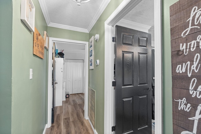 hallway featuring baseboards, visible vents, wood finished floors, a textured ceiling, and crown molding