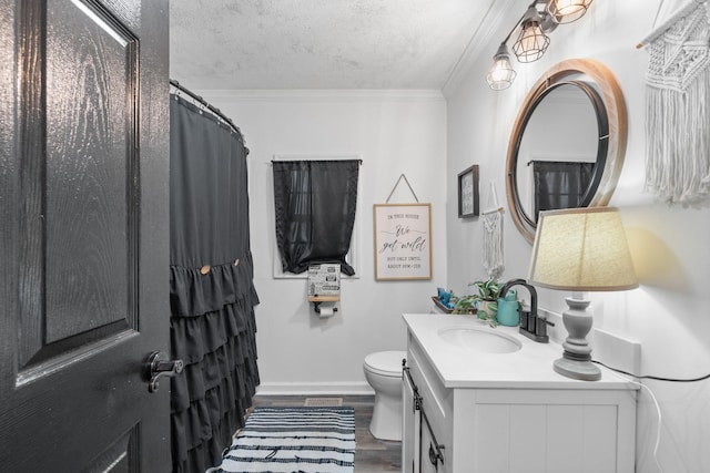 bathroom featuring a textured ceiling, wood finished floors, vanity, and crown molding