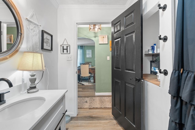 bathroom with crown molding, vanity, and wood finished floors