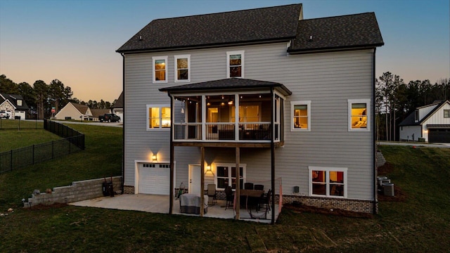 rear view of property with a yard, an attached garage, a patio, and fence