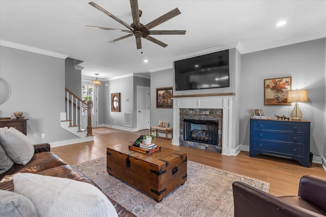 living area with stairs, wood finished floors, a ceiling fan, and ornamental molding