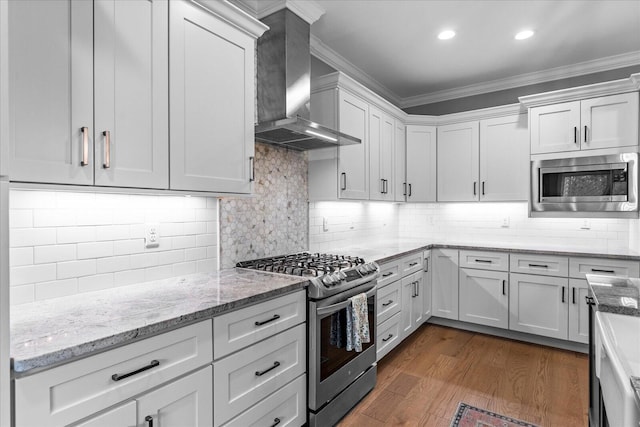 kitchen with appliances with stainless steel finishes, wall chimney exhaust hood, dark wood-type flooring, and crown molding
