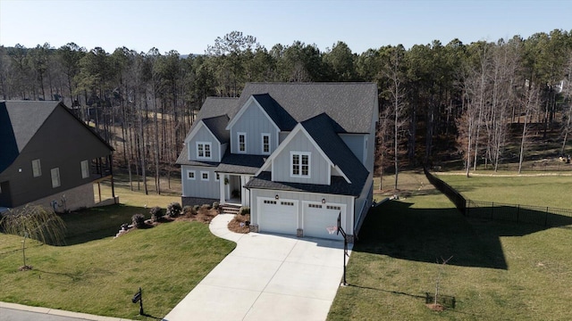 view of front of house with a view of trees, board and batten siding, concrete driveway, a front yard, and a garage