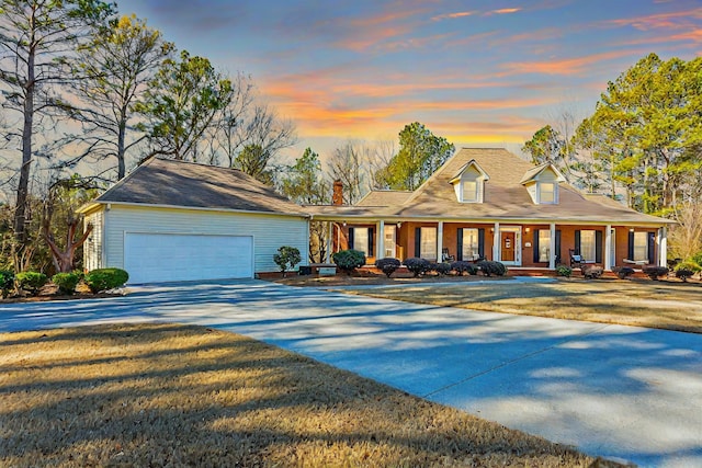 view of front of home featuring a porch, a garage, an outdoor structure, concrete driveway, and a front yard