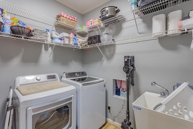 laundry area featuring a sink, laundry area, crown molding, and washer and dryer