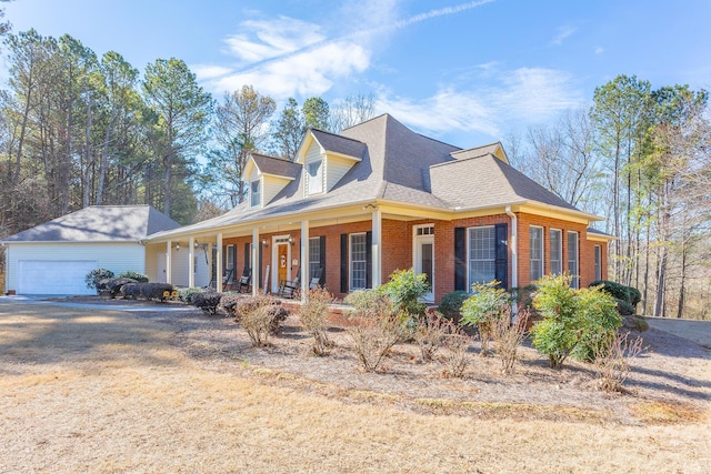 view of front of property featuring a garage, a shingled roof, an outdoor structure, a porch, and brick siding