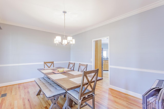 dining room with ornamental molding, baseboards, light wood finished floors, and an inviting chandelier