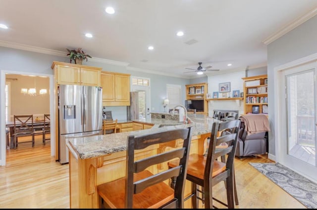 kitchen featuring light wood-style flooring, a sink, ornamental molding, stainless steel fridge with ice dispenser, and light brown cabinetry