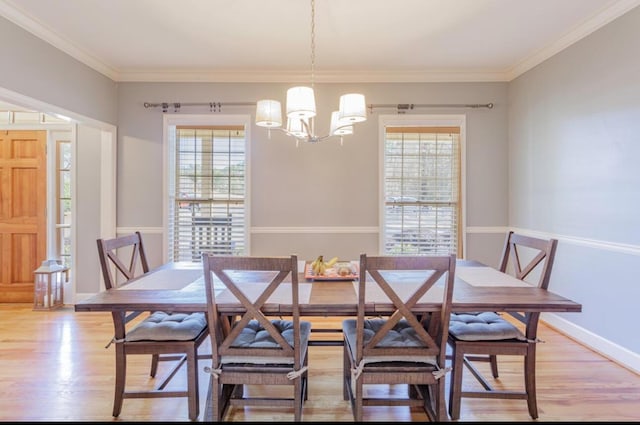 dining space featuring light wood-style floors, plenty of natural light, ornamental molding, and a chandelier