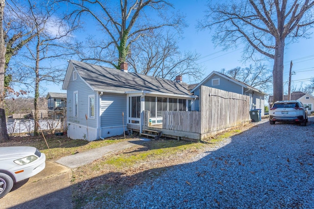 exterior space with gravel driveway, crawl space, a chimney, and a sunroom