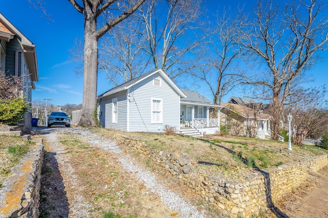 view of front of home featuring dirt driveway and a porch