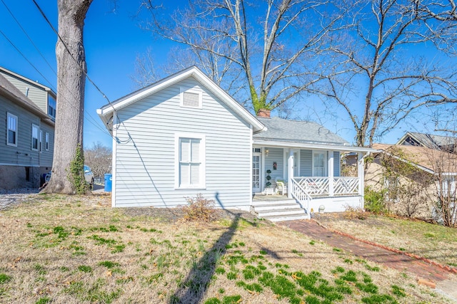 view of front facade with covered porch and a chimney