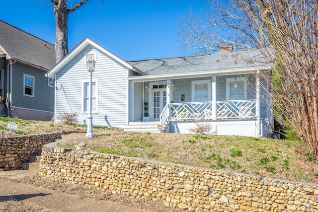 single story home with a chimney and a porch