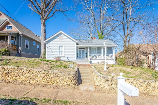 view of front of home with covered porch, a chimney, and french doors