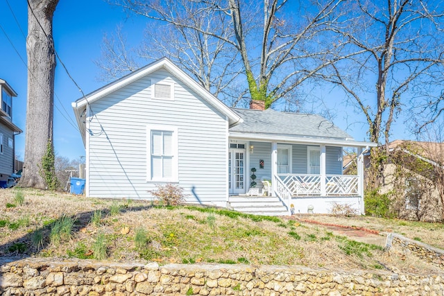 view of front of property with a porch, a shingled roof, and a chimney